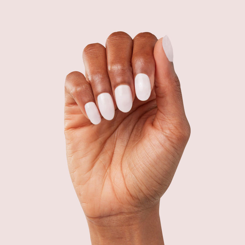 Close-up of a finished white press-on manicure against a soft neutral background